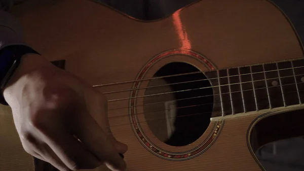 Close-up de homem tocando guitarra. HDR. O homem toca violão simples em casa. Jovem toca guitarra na semi-escuridão — Fotografia de Stock