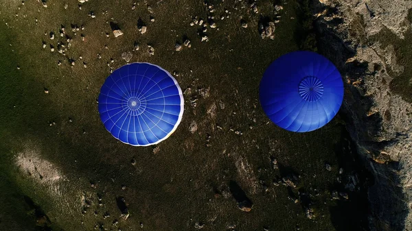 Vista aérea de dois balões azuis de ar quente voando acima das estradas rurais e árvores e campos verdes. Atingido. Voando no céu acima da natureza verde. — Fotografia de Stock