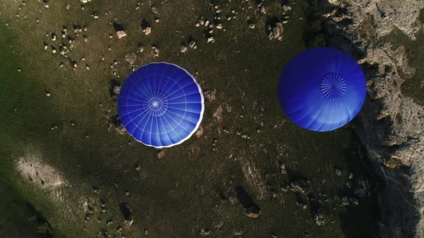 Kırsal bölgedeki iki renkli sıcak hava balonunun üst görüntüsü. Vuruldu. Aerostat taşların ve tarlaların üzerinde uçuyor, macera kavramı. — Stok video