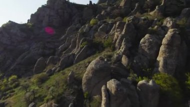 Kayalık yamaçlarda dikilen taşlar. Vuruldu. Dağ yamaçlarındaki kaya oluşumları ve aşınma çeşitliliği. Kayalık kayalara ve sütunlara uçmak ruhu büyülüyor.