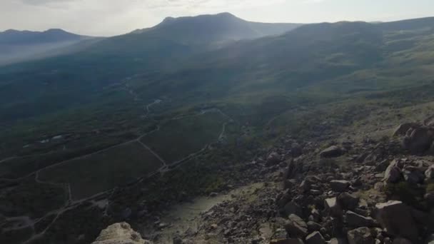 Descent from rocky cliff. Shot. Extreme fast flight from side of rocky mountain on sunny day. Descent by wingsuit or quadrocopter with flight dive on rocky slopes — Stock Video