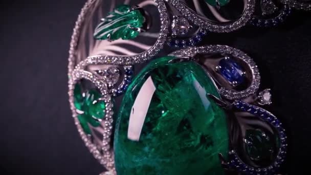 Close up of the beautiful jewelry with precious stones, sapphires, diamonds, and emerald. Video. Luxury pendant isolated on black background of a jewelry holder. — Stock Video