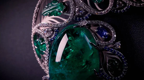 Primer plano de las hermosas joyas con piedras preciosas, zafiros, diamantes y esmeralda. Vídeo. Colgante de lujo aislado sobre fondo negro de un joyero. — Foto de Stock
