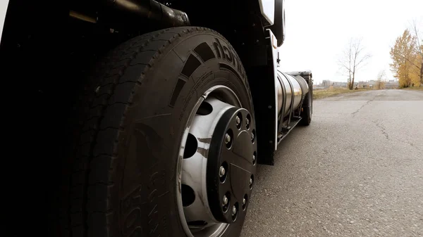 Крупный план белого грузовика, проходящего по шоссе. Сцена. Вид на деталь колеса и шины грузовика на сухом асфальте шоссе. — стоковое фото
