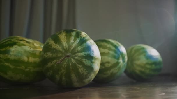 Feche de quatro melancias inteiras em uma mesa marrom de madeira em casa. Vídeo. Vitaminas de verão, bagas maduras na cozinha em casa. — Vídeo de Stock