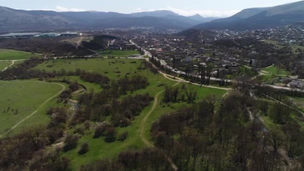 Charmig liten stad belägen i den gröna dalen, ekologisk plats för boende. Skjuten. pittoreska naturlandskap med ängar, gröna träd och berg långt bort. — Stockvideo