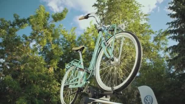 Onderaanzicht van een licht turquoise retro fiets op een standaard buiten op een zomerse zonnige dag. Een video. Ouderwetse fiets op de achtergrond van groene bomen. — Stockvideo