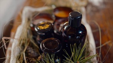 Kokulu mumlar, yağ şişesi ve kozalaklı kozalaklı kozalaklı kozalaklı kozalaklı ağaç dallarıyla birlikte Aromaterapi masası. Video kaydı. Dekoratif kutunun üzerine doğal mumlar ve ahşap masa arkaplanı yağlı..