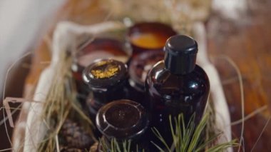 Kokulu mumlar, yağ şişesi ve kozalaklı kozalaklı kozalaklı kozalaklı kozalaklı ağaç dallarıyla birlikte Aromaterapi masası. Video kaydı. Dekoratif kutunun üzerine doğal mumlar ve ahşap masa arkaplanı yağlı..