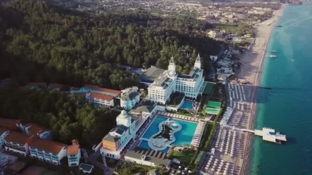 Vista aérea de um resort de luxo localizado junto ao mar. Vídeo. Voando sobre o deslumbrante território circundante do hotel com a costa do mar, piscina, cais e floresta verde. — Vídeo de Stock