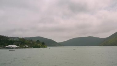 Yeşil dağları ve kıyıları olan bulutlu güzel manzaranın en üst manzarası. Başla. Yeşil dağlı yaz manzarası ve kasaba kıyısı yakınında su.