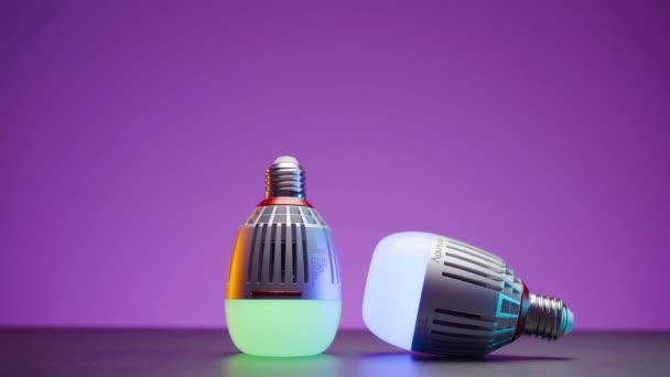 Light bulbs glow in different colors. Action. Two modern light bulbs glow and change colors. Light bulbs with effect of changing colors for party atmosphere or comfort — Stock Video