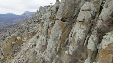 Dağların kayalık arazisinin en üst manzarası. Vuruldu. Çok çeşitli rahatlamalarla kayalık dağ yamaçlarında uçmak. Dağlık arazide kayaların çeşitliliği ve erozyon gidericiler