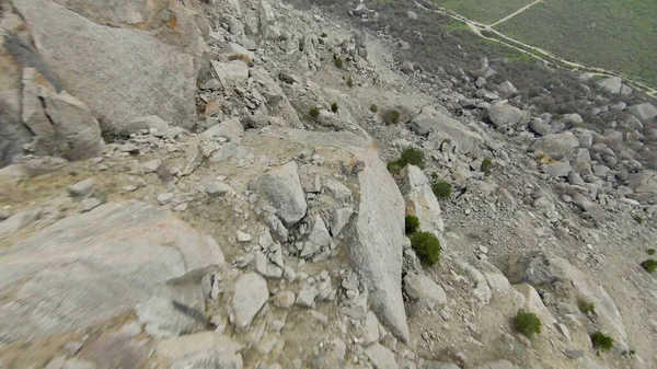 Zejście ze skalistego klifu. Postrzelony. Ekstremalnie szybki lot ze strony skalistej góry w słoneczny dzień. Zejście wingsuit lub quadrocopter z nurkowaniem w locie na skalistych stokach — Zdjęcie stockowe