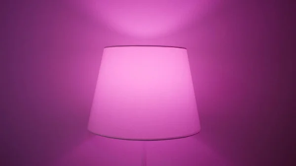Domácí lampa s různými barvami. Akce. Podlahová lampa s vícebarevnou žárovkou, která mění barvy. Lampa vytváří útulnou atmosféru domácí párty — Stock fotografie