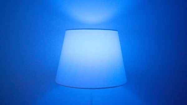 Domácí lampa s různými barvami. Akce. Podlahová lampa s vícebarevnou žárovkou, která mění barvy. Lampa vytváří útulnou atmosféru domácí párty — Stock fotografie