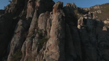 Kayalık dağ yamaçlarına yakın uçmak alışılmadık şekillerde kayalar. Vuruldu. Güneşli bir günde mavi gökyüzü altında inanılmaz doğal oluşumların havadan görünüşü.