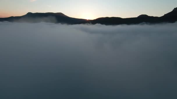 Letecký pohled na krásný východ slunce nad horami a hustou mlhu. Zastřelen. Úžasný let nad bílými mraky směrem k pohoří. — Stock video