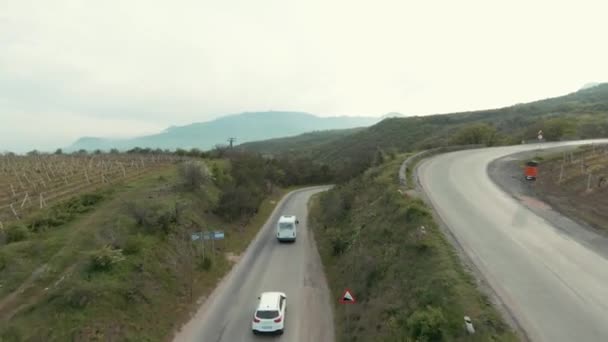 Veduta aerea della parte posteriore del trasporto in movimento su una stretta autostrada piegatura. Gli hanno sparato. Bella giornata estiva in campagna con verde valle. — Video Stock