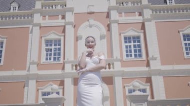 Lüks eski binada zarif bir gelin. Başla. Saray 'da zarif beyaz elbiseli güzel bir kadın. Şatafatlı gelin güneşli bir günde sarayın arka planında zarifçe poz verir.