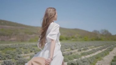 Beyaz elbiseli güzel bir kadın tarlada koşuyor. Başla. Kadın saçı ve elbisesi koşarken çok güzel çırpınıyor. Beyaz uzun elbiseli bir kadının tarlada koşması ağır çekimde