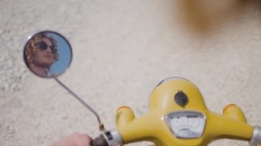 Scooter 'daki çekici genç adamın yakın çekimi. Başla. Güneşli bir günde scooter süren acımasız bir adam. Şık bir adam klasik scooter kullanıyor.