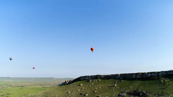 Bottom view of colorful air balloons soaring in the sky above geen meadow. Shot. Exploring nature from a birds eye view.