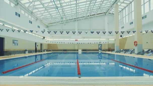 Spor kompleksindeki bir yüzme havuzunun içine bak. Video kaydı. Cam tavanlı ve sakin suyu olan güzel bir yüzme havuzu.. — Stok video
