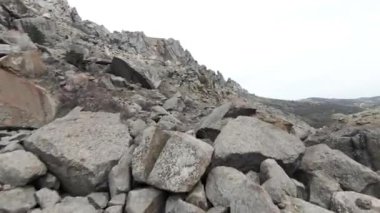 Bulutlu arka planda yüksek dağ yamacının havadan görünüşü. Vuruldu. Tepedeki doğal oluşumlar veya uyuyan volkan..