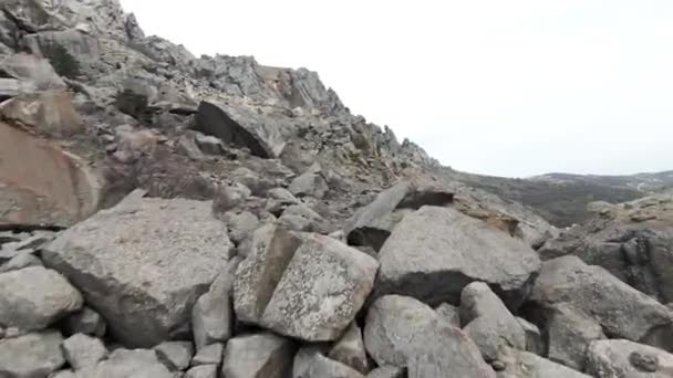 Vue aérienne d'une pente de haute montagne pierreuse sur fond de ciel nuageux. Fusillade. Formations naturelles sur une colline ou un volcan endormi. — Video