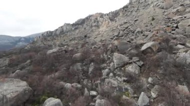 Bulutlu arka planda yüksek dağ yamacının havadan görünüşü. Vuruldu. Tepedeki doğal oluşumlar veya uyuyan volkan..