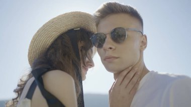 Parlayan güneşin arka planında güzel genç bir çift. Başla. Şık bir çift birbirine sevgiyle bakar. Genç çift parlak güneşin arka planında birbirlerine yakından bakıyorlar.