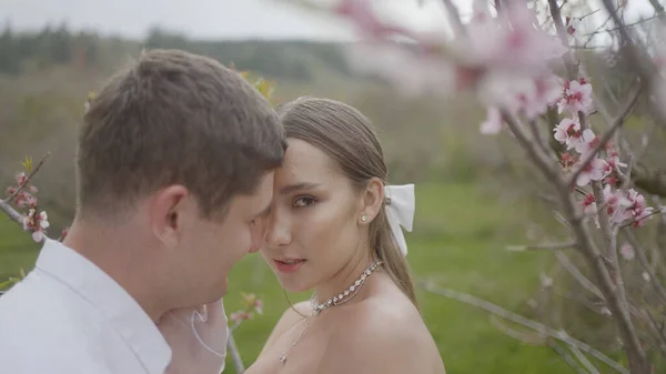 Frischvermählte berühren einander sanft und leidenschaftlich. Handeln. Schöne Paar leidenschaftlich berühren einander vor dem Hintergrund der Natur. Elegantes Ehepaar posiert bei Hochzeit leidenschaftlich in der Natur — Stockfoto