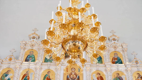 Keresztény ortodox templom belső fehér és arany színekben. Videó. Csillár mesterséges gyertyákkal a templomban ikonosztázissal. — Stock Fotó