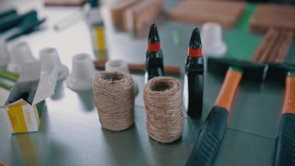 Primo piano di un tavolo con molti oggetti per l'attività artigianale. Un video. Colla, corda di spago, martelli e tavola di legno, concetto di creatività. — Video Stock