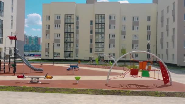 Un moderno parque infantil está vacío en el nuevo complejo residencial moderno. Vídeo. Hermoso patio al aire libre en un día soleado de verano. — Vídeo de stock