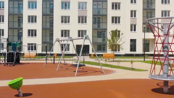 Un moderno parque infantil está vacío en el nuevo complejo residencial moderno. Vídeo. Hermoso patio al aire libre en un día soleado de verano. — Vídeo de stock