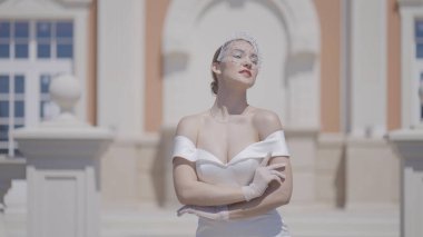 Zarif gelin eski binanın arka planında poz veriyor. Başla. Beyaz elbiseli güzel kadın sarayda zarif poz veriyor. Zarif jestleri olan muhteşem gelin.