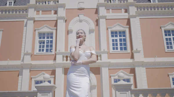 Elegáns menyasszony egy fényűző régi épületben. Felvétel. Gyönyörű nő elegáns fehér ruhában a palotában. Luxus menyasszony elegánsan pózol a palota hátterében a napsütéses napon — Stock Fotó