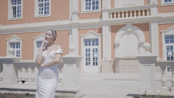 Elegante novia en palacio. Acción. Preciosa mujer en vestido blanco en el fondo del edificio viejo. Mujer con elegante vestido blanco posa en palacio —  Fotos de Stock