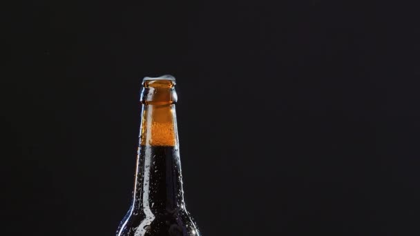Primer plano de una mano abriendo una botella de vidrio. Vídeo. Bebida alcohólica aislada sobre fondo negro, concepto de fiesta. — Vídeo de stock