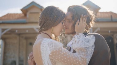 Hippi yeni evliler kucaklaşır. Başla. Güzel bir çift, hippi tarzı gelinlikler içinde birbirlerine sarılıyorlar. Hippi tarzı giysiler içinde yeni evliler tutkuyla kucaklaşır.