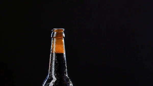 Närbild av en hand som öppnar en glasflaska. Videon. Alkoholhaltig dryck isolerad på svart bakgrund, begreppet parti. — Stockfoto