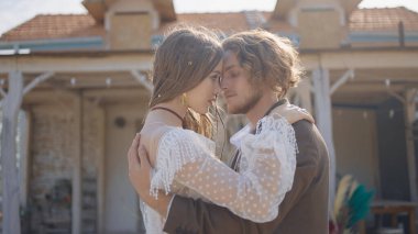 Hippi yeni evliler kucaklaşır. Başla. Güzel bir çift, hippi tarzı gelinlikler içinde birbirlerine sarılıyorlar. Hippi tarzı giysiler içinde yeni evliler tutkuyla kucaklaşır.