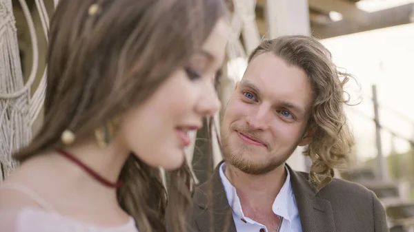 Schöner Mann schaut junge Frau an, die verliebt redet. Handeln. Schönes Paar in Outfits plaudert auf Party oder Event. Attraktiver Mann lächelt junge Frau beim Reden an — Stockfoto