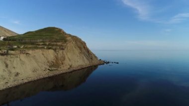 Açık deniz ve küçük yeşil bir adanın göz kamaştırıcı hava manzarası. Vuruldu. Sakin mavi deniz suyunun yanında yalnız evleri olan uçurumlar soluk kesici yeşil çimenler..