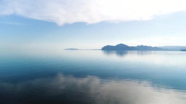 Güzel bir gün doğumu ve gölün üzerinde sabah bulanıklığı. Vuruldu. İnanılmaz mavi gökyüzü ve sakin su, sis ve tepelerin siluetleri.
