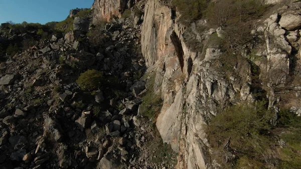 Velocidade voo mergulho perto de encostas rochosas da montanha sob o sol brilhante. Atingido. Vista aérea de falésias naturais com vegetação. — Fotografia de Stock