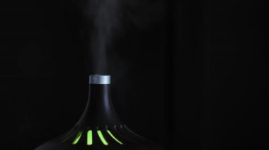 Siyah arka planda izole edilmiş gece lambası olan şık bir hava nemlendiricisi. Kavram. Konfor kavramı ve ev tarzı, beyaz buhar yükseliyor..