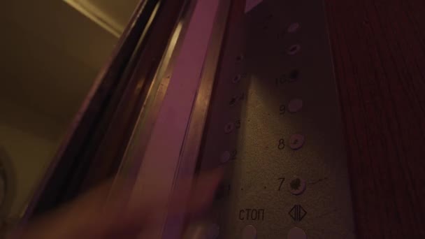 女性の手を閉じるには、エレベーターボタンを押します。ストック映像だ。8階と9階建てのエレベーターにはカラフルな照明があります。. — ストック動画